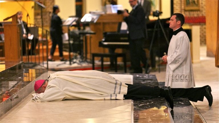 Bishop Dennis Sullivan prostrates himself at the altar during an evening of prayer for the victims of sexual abuse by Catholic clergy on Sept. 28, 2018, in Blackwood, New Jersey. (Miguel Martinez for WHYY)