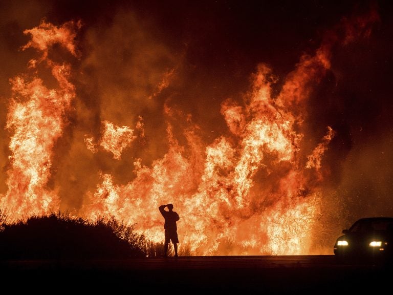 A motorists on Highway 101 watches flames from the Thomas fire leap above the roadway north of Ventura, Calif., in December 2017. Hundreds of homes were destroyed in what was then California's most destructive wildfire. (Noah Berger/AP)