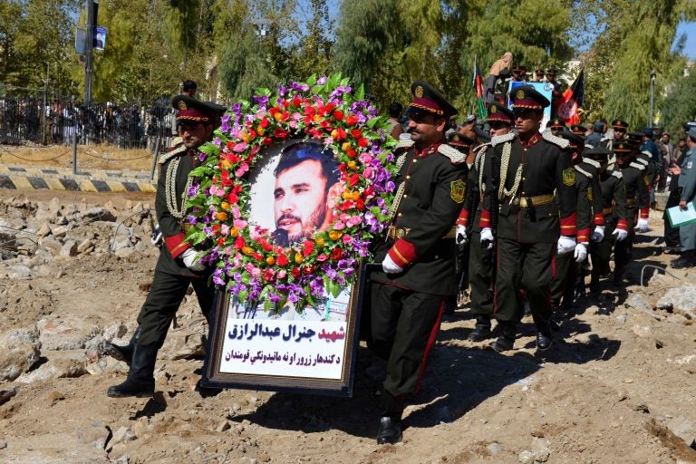 Guards of honor carry a photo of Brig. Gen. Abdul Raziq, Kandahar police chief, at his burial ceremony in Kandahar in October. (AP)