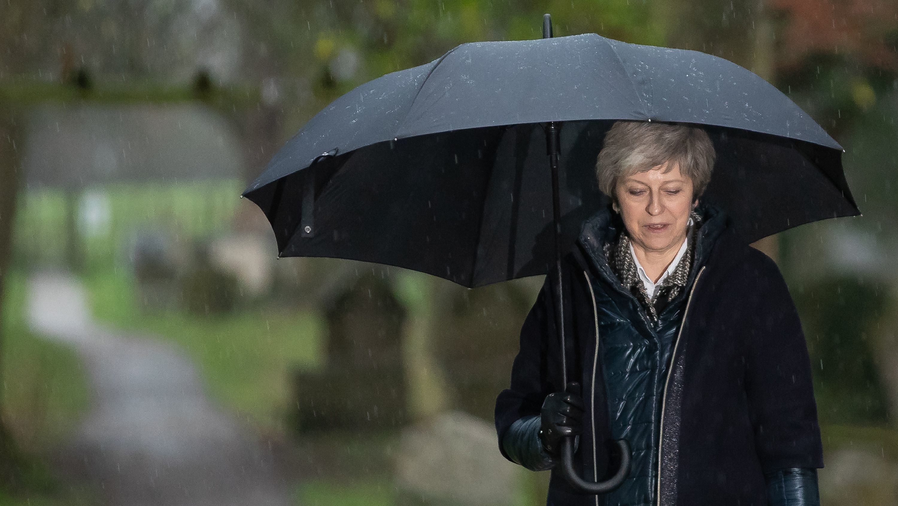 British Prime Minister Theresa May leaves a church service west of London in Sunday's pouring rain