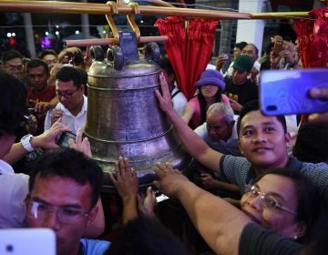 Residents take photos and try to touch one of the three Balangiga church bells after a ceremony returning them to the church in the town of Balangiga in the Philippines on Dec. 15, 2018. (Ted Aljibe/AFP/Getty Images)