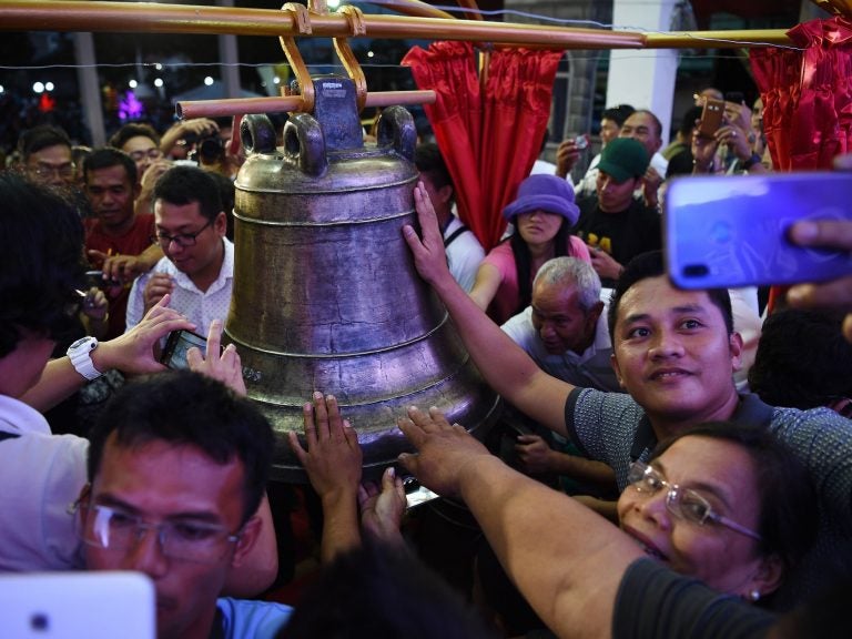 Residents take photos and try to touch one of the three Balangiga church bells after a ceremony returning them to the church in the town of Balangiga in the Philippines on Dec. 15, 2018. (Ted Aljibe/AFP/Getty Images)