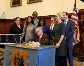 Mayor Jim Kenney signs a bill Tuesday authorizing the Philadelphia Energy Authority — an independent municipal authority set up specifically to reduce the city's energy's consumption — to enter into a contract to purchase 22 percent of its power from solar provider Community Energy. (Tom MacDonald/WHYY)