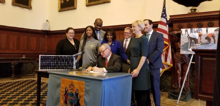 Mayor Jim Kenney signs a bill Tuesday authorizing the Philadelphia Energy Authority — an independent municipal authority set up specifically to reduce the city's energy's consumption — to enter into a contract to purchase 22 percent of its power from solar provider Community Energy. (Tom MacDonald/WHYY)