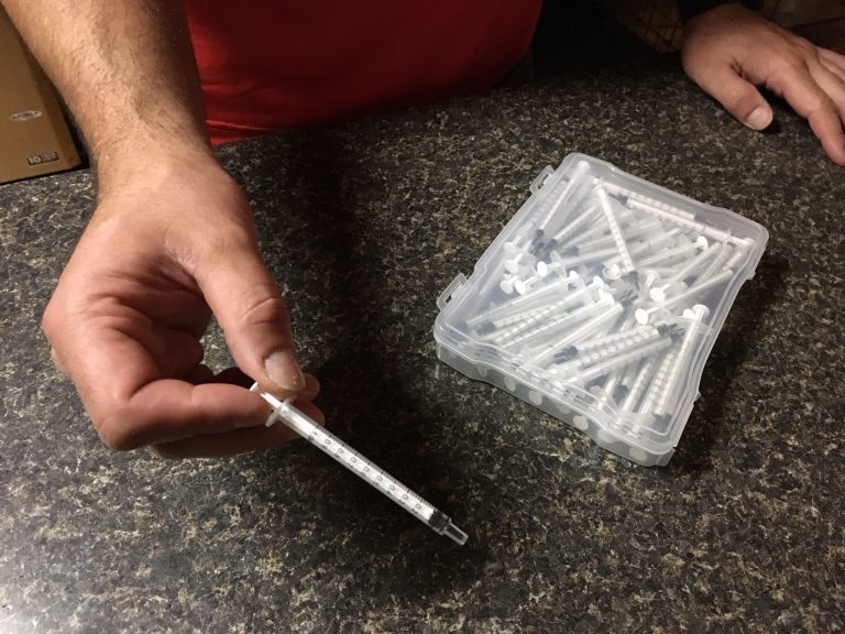 Chris holds a plastic syringe he and his wife use to administer homemade medical marijuana oil to their 13-year-old son, Dylan, who has autism.
(Lynn Arditi/The Public's Radio)