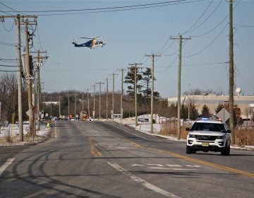 A state police helicopter lands near a UPS facility in Logan Township where two women were held hostage by a gunman. (Emma Lee/WHYY)