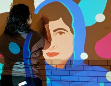 Anisa Shafiq uses a slide projector to mark out a mural of Malala Yousafzai in a hallway of Kensington High School.