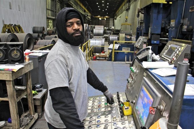 Isaac Pernell of Woodlynne, who started at Camden Yards five years ago in the packaging department, now operates a leveler, which straitens out the curled steel that arrives in rolls. (Emma Lee/WHYY)