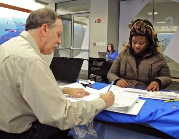 Marshal Granor of the Hebrew Free Loan Association writes a check for $1,250 to Latashah Sharp, a federal employee who has fallen behind on her rent since the government shutdown began. An employee of the Transportation Security Administration at Philadelphia airport, Sharp has continued working without pay. An anonymous $500,000 donation made the interest free loans to federal employees possible. (Emma Lee/WHYY)