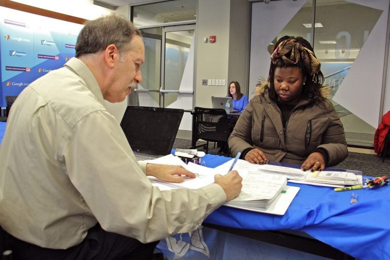 Marshal Granor of the Hebrew Free Loan Association writes a check for $1,250 to Latashah Sharp, a federal employee who has fallen behind on her rent since the government shutdown began. An employee of the Transportation Security Administration at Philadelphia airport, Sharp has continued working without pay. An anonymous $500,000 donation made the interest free loans to federal employees possible. (Emma Lee/WHYY)