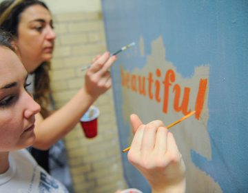 Kensington High School biology teacher Victoria Erickson (right) and her friend Megan Nardi, work on a mural on Kensington High School's ground floor.