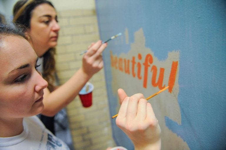 Kensington High School biology teacher Victoria Erickson (right) and her friend Megan Nardi, work on a mural on Kensington High School's ground floor.