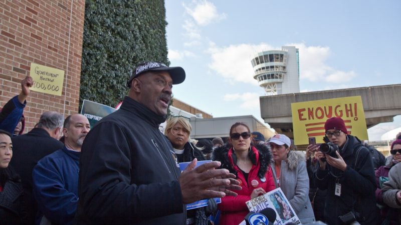 U.S. Congressman Dwight Evans calls for an end to government shutdown outside Philadelphia International airport Friday. (Kimberly Paynter/WHYY)