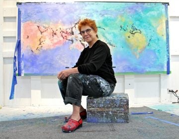 Artist Diane Burko poses in front of an unfinished work at her Center City studio.