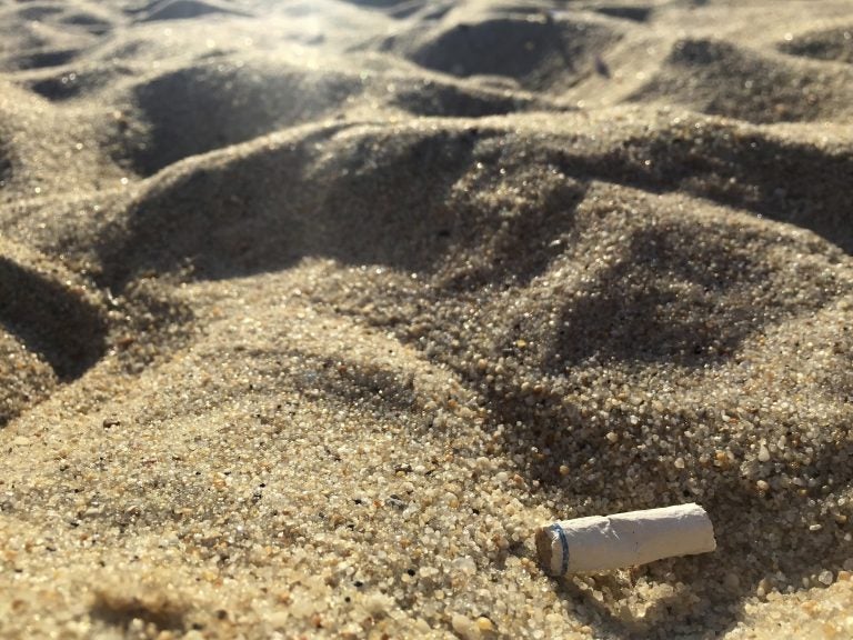 In this Aug. 25, 2018, photo a cigarette butt lies on the sand at  beach in Middletown, N.J. Democratic Gov. Phil Murphy signed the bill banning smoking at the state's public beaches and parks in July, though local communities can opt out and designate small smoking sections. The law takes effect Jan. 16, 2019. (AP Photo/Jenny Kane)