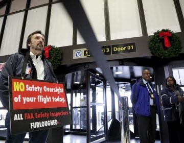 Federal Aviation Administration employee Michael Jessie, who is currently working without pay as an aviation safety inspector for New York international field office overseeing foreign air carriers, holds a sign while attending a news conference at Newark Liberty International Airport, Tuesday, Jan. 8, 2019, in Newark, N.J. U.S. Sens. Cory Booker and Bob Menendez called a news conference at the airport to address the partial government shutdown, which is keeping some airport employees working without pay. (Julio Cortez/AP)
