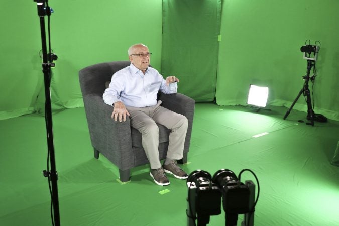 This August 2018 photo shows Holocaust survivor Max Glauben sitting in an interactive green screen room while filming a piece for the Dallas Holocaust Museum in Dallas. (McGuire Boles/Dallas Holocaust Museum via AP)