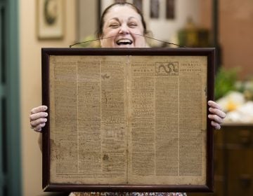 In this Thursday, Oct. 25, 2018 file photo, Heather Randall displays a Dec. 28, 1774 Pennsylvania Journal and the Weekly Advertiser at the Goodwill Industries South Jersey in Bellmawr, N.J.  An original 1774 Philadelphia newspaper that was discovered at a New Jersey Goodwill is heading to a Philadelphia philosophy society founded by Benjamin Franklin. (Matt Rourke/AP)