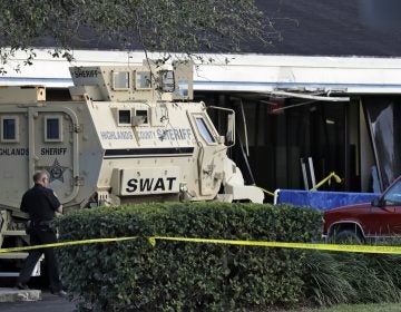 A Sebring, Fla., police officer stands near a Highlands County Sheriff's SWAT vehicle that is stationed in front of a SunTrust Bank branch, Wednesday, Jan. 23, 2019, in Sebring, Fla., where authorities say five people were shot and killed. (Chris O'Meara/AP Photo)