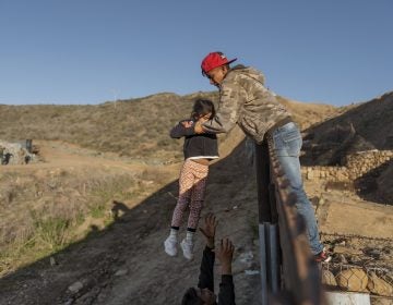 In this Jan. 3, 2019, file photo, a migrant from Honduras pass a child to her father after he jumped the border fence to get into the U.S. side to San Diego, Calif., from Tijuana, Mexico. The Trump administration expects to launch a policy as early as Friday, Jan. 25, that forces people seeking asylum to wait in Mexico while their cases wind through U.S. courts, an official said, marking one of the most significant changes to the immigration system of Donald Trump's presidency. (Daniel Ochoa de Olza, AP Photo)