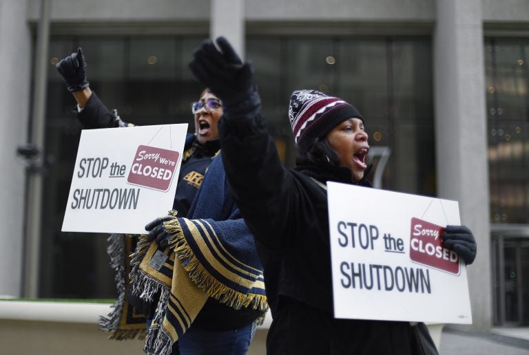 In this Jan. 10, 2019 file photo Cheryl Monroe, (right), a Food and Drug Administration employee, and Bertrice Sanders, a Social Security Administration employee, rally to call for an end to the partial government shutdown in Detroit. The government shutdown left an especially painful toll for African-Americans who make up nearly 20 percent of the federal workforce and historically have been on the low end of the government pay scale. (Paul Sancya/AP Photo, file)