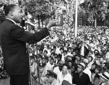 A line of police stands in front of platform from which Dr. Martin Luther King speaks during mass meeting in front of all-white Girard College in Philadelphia August 4, 1965. Dr. King said the wall surrounding the school was a symbol of evil and called for continued efforts to integrate the school.