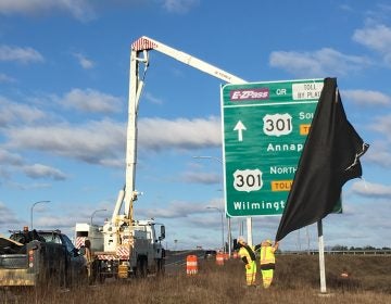 Workers unveil signs directing drivers to the new Route 301 near Middletown. (Mark Eichmann/WHYY)