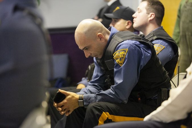 Vineland Police Officer Luis Rivera look down as audience members offer their remarks about policing . Gurbir S. Grewal and Jennifer Webb-McRae host community listening session on Police use fo force on Jan. 23, 2019. (Miguel Martinez for WHYY)during a community listening session in Bridgeton, N.J., Jan. 23, 2019. (Miguel Martinez for WHYY)