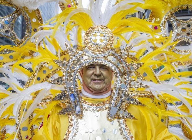 Ed Cox of Golden Sunrise called last years cold conditions the worst parade weather ever. This year he worried about controlling his costume with the winds gusts as he headed down Broad St.  (Jonathan Wilson for WHYY)