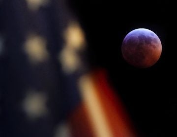 A U.S. flag flies in the foreground of this image of the moon during the lunar eclipse as seen from Washington, D.C., on Sunday night (J. David Ake/AP)