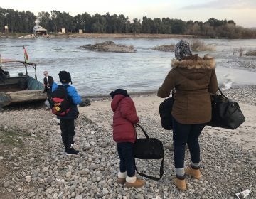 Mahmud, 11, Ayyub, 7, and their mother, Felicia Perkins-Ferreira, walk toward the boat that will take them out of Syria, across the river to Iraq, so they can start their journey home to Trinidad. (Ruth Sherlock/NPR)