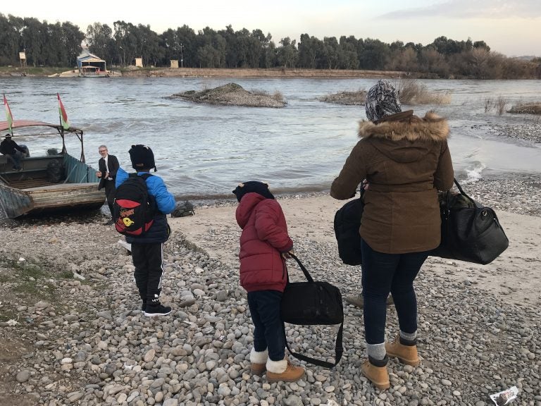 Mahmud, 11, Ayyub, 7, and their mother, Felicia Perkins-Ferreira, walk toward the boat that will take them out of Syria, across the river to Iraq, so they can start their journey home to Trinidad. (Ruth Sherlock/NPR)