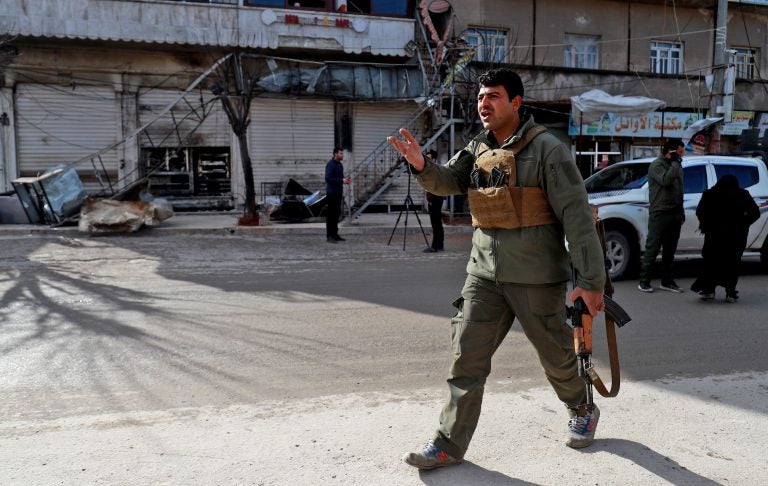A security force member walks outside a shuttered restaurant Thursday in Manbij, Syria, the site of a suicide attack that killed more than a dozen people, including four Americans, a day earlier. The Islamic State claimed responsibility for the attack. (Delil Souleiman /AFP/Getty Images)