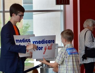 A volunteer hands out a poster as Vermont independent Sen. Bernie Sanders was set to address a 'Medicare for All' rally in downtown Columbia, S.C. on Saturday, Oct. 20, 2018. (Meg Kinnard/AP Photo)