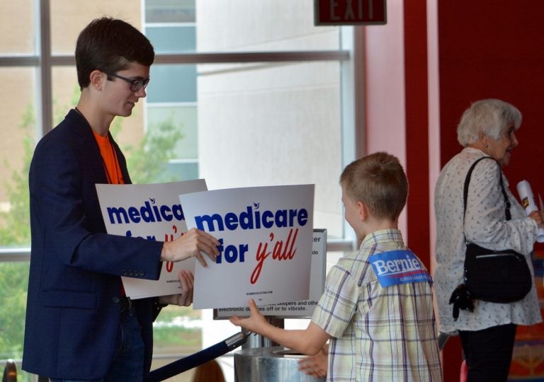 A volunteer hands out a poster as Vermont independent Sen. Bernie Sanders was set to address a 'Medicare for All' rally in downtown Columbia, S.C. on Saturday, Oct. 20, 2018. (Meg Kinnard/AP Photo)