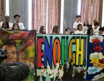 Students hold up mural created for King Day of Service. (Tom MacDonald/WHYY)