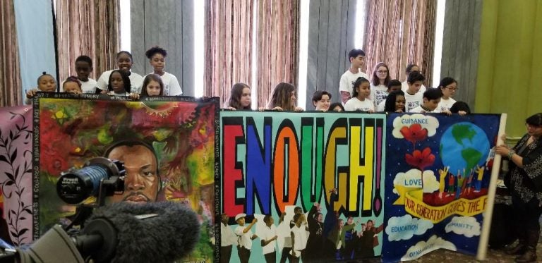 Students hold up mural created for King Day of Service. (Tom MacDonald/WHYY)