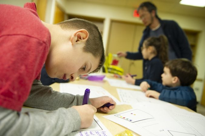 Olney Culture Lab Project Director Ambrose Liu, (background), plays with children whose parents were attending Uneven Play: A Community Dinner and Conversation at St Pauls Lutheran Church in Olney. (Jonathan Wilson for WHYY)