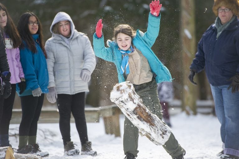 Troop 19 member Josie Provencher tosses a log at the log hurling station of the Klondike Derby. (Jonathan Wilson for WHYY)