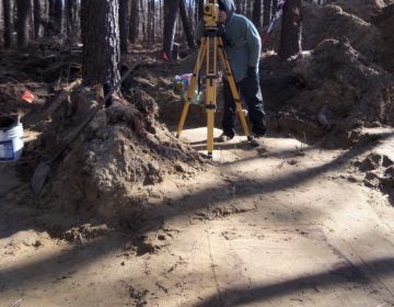 John Potts is using a total station to map the site. Graves can be seen  as grey-ish stains in the soil. (Jill Showell/Edward Otter, Inc.)