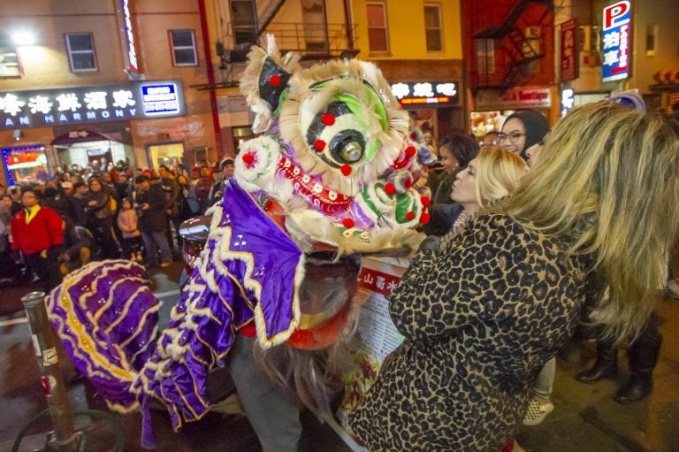 A woman blows a kiss to one of the lions dancing on Race Street during the Chinese New Year celbration. (Jonathan Wilson for WHYY)