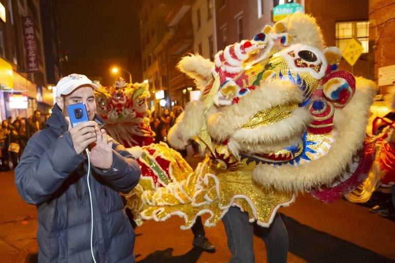 Josh Millman takes a selfie with one of the cavorting lions dancing on Cherry Street in Chinatown. Millman and hundreds of others came to Chinatown late Monday evening to welcome the Year of the Pig.