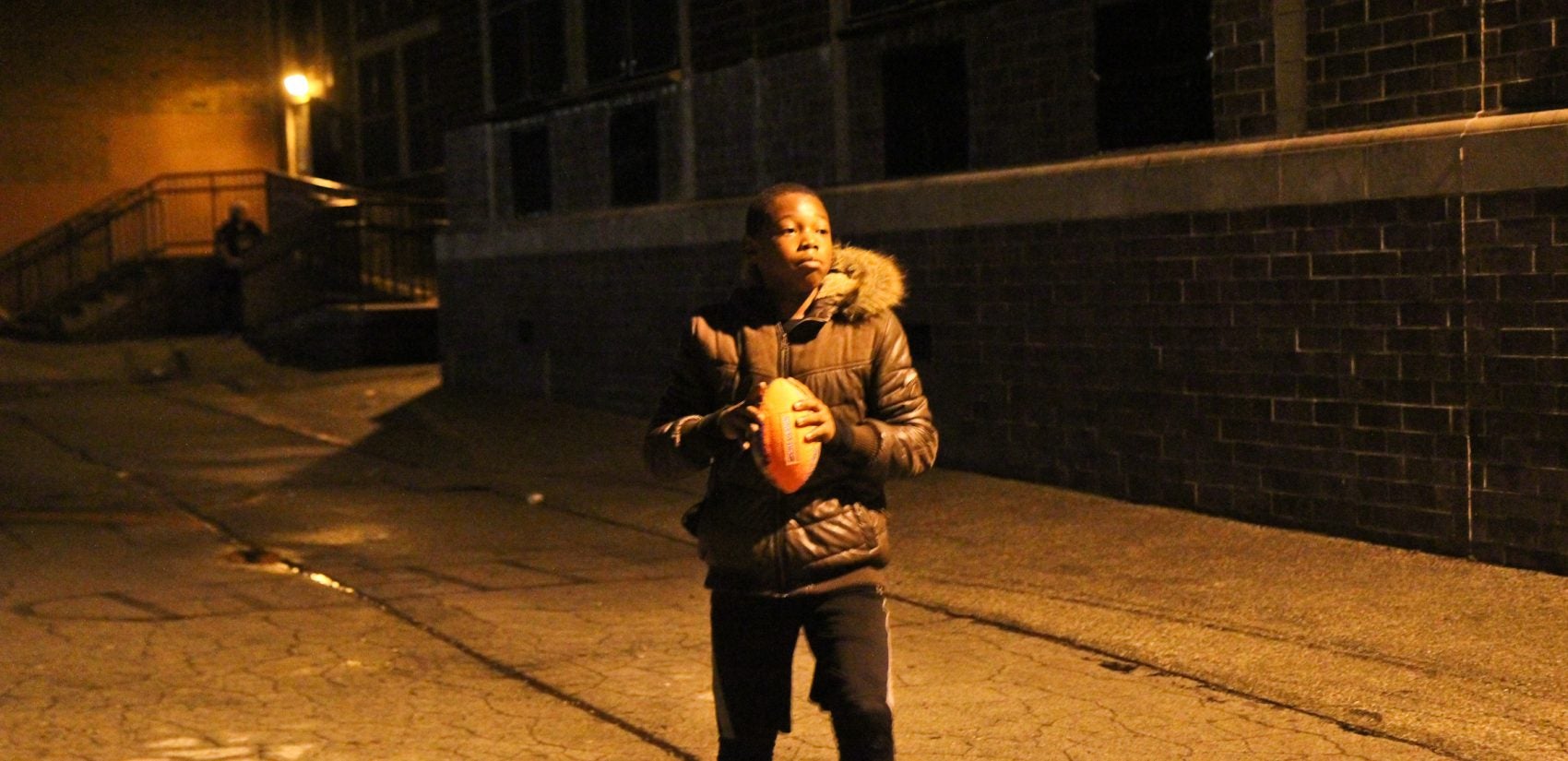 Maurice Barnes tosses a football in the schoolyard behind Lowell Elementary School. (Kimberly Paynter/WHYY)