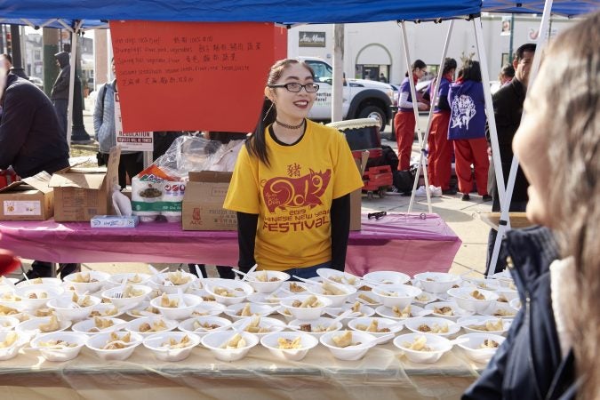 Amy Lee, 21, of Northeast Philadelphia, volunteers at the 2019 Chinese New Year Festival serving cheese wonton and other traditional Chinese foods. (Natalie Piserchio for WHYY)