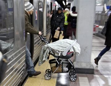 A man pushes a stroller off a SEPTA subway train at the 8th and Market station. (Emma Lee/WHYY)