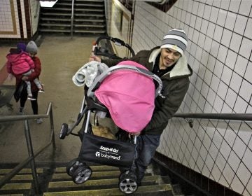 A man carries a stroller up the stairs at the 8th and Chestnut exit from the Market Frankford line. (Emma Lee/WHYY)