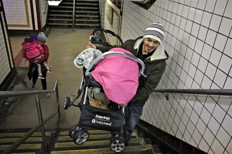 A man carries a stroller up the stairs at the 8th and Chestnut exit from the Market Frankford line. (Emma Lee/WHYY)