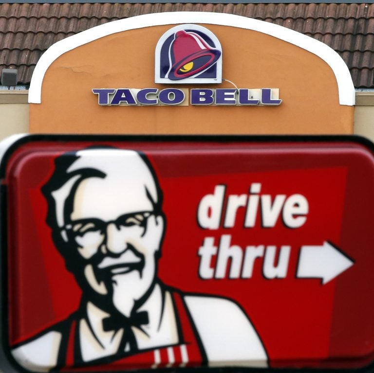 This Jan. 31, 2014, file photo, shows a Taco Bell facade behind a KFC drive-thru sign (Elise Amendola/AP Photo, File)