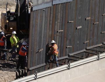 In this Tuesday, Jan. 22, 2019, photo, workers place sections of metal wall as a new barrier is built along the Texas-Mexico border near downtown El Paso. (AP Photo/Eric Gay)