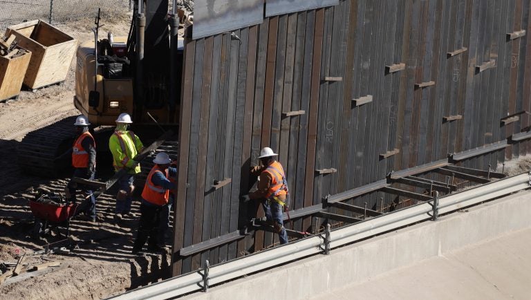 In this Tuesday, Jan. 22, 2019, photo, workers place sections of metal wall as a new barrier is built along the Texas-Mexico border near downtown El Paso. (AP Photo/Eric Gay)